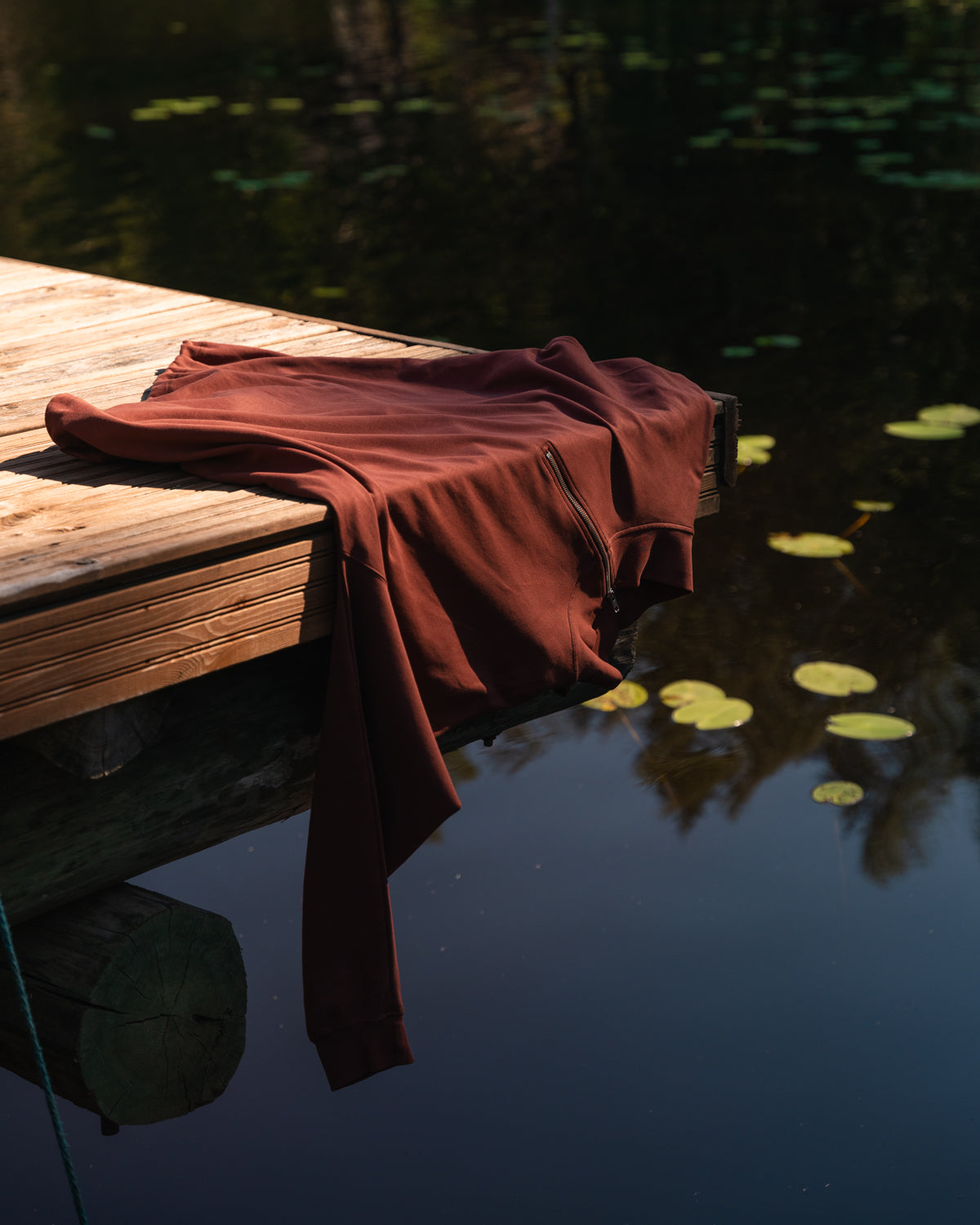 Ruosteenpunainen half-zip paita laiturilla.